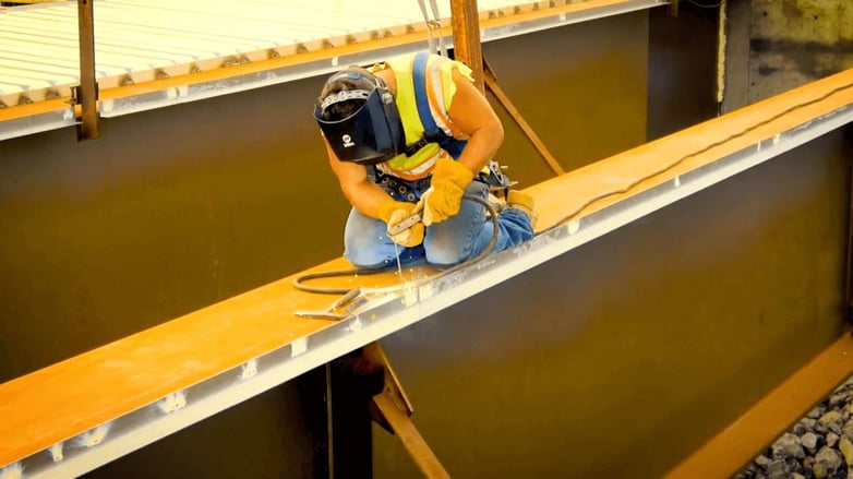 CAHill Tech. Construction worker welds on steel beam